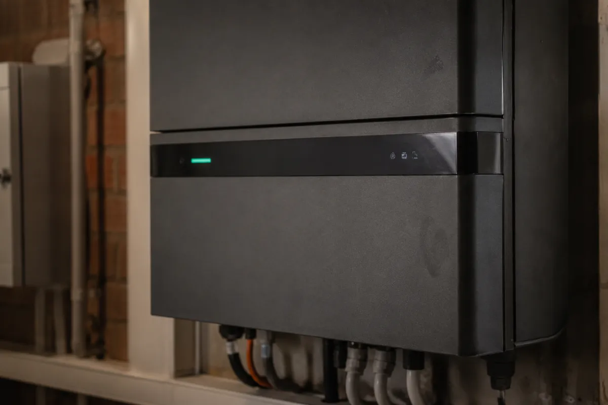 Weißer Sungrow Hybrid-Wechselrichter mit Kabelanschlüssen an der Wand im Hauswirtschaftsraum